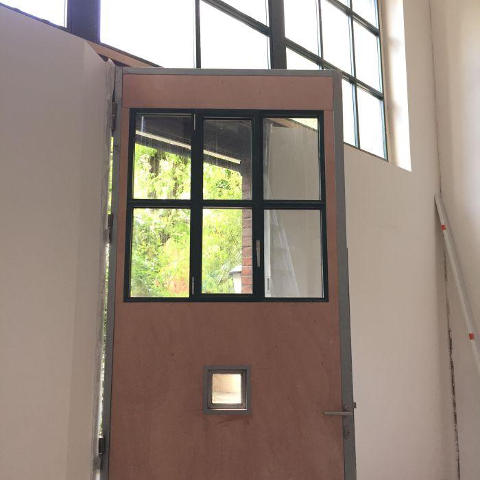 Porte d'atelier avec une verrière avec un ouvrant intégré