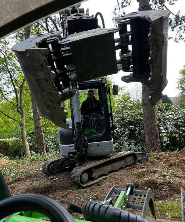 Ein Mann fährt einen kleinen Bagger durch einen Wald.