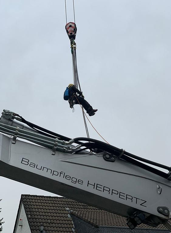 Ein Mann hängt an einem Kran im Himmel.