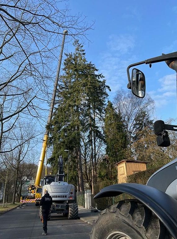 Ein Mann läuft neben einem Traktor und einem Kran eine Straße entlang.