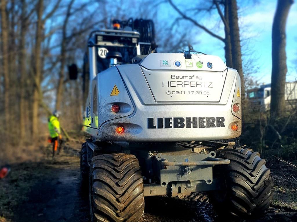 Ein Liebherr-Bagger steht auf einem Feldweg im Wald.