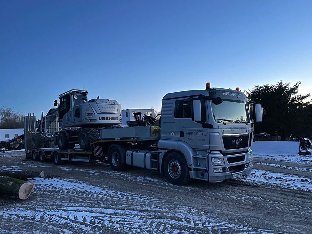 Ein großer LKW transportiert einen großen Bagger auf einem Anhänger.