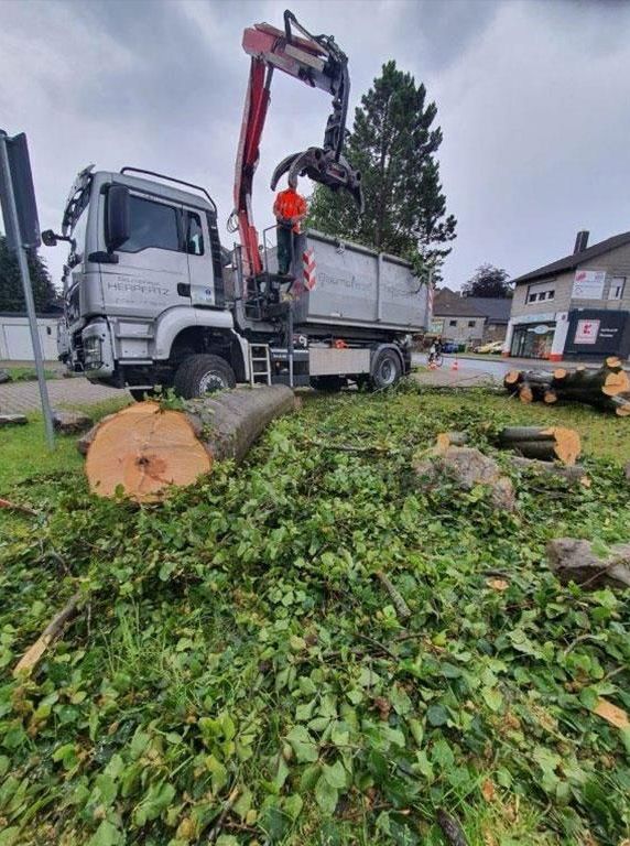 Ein Mann steht neben einem LKW, an dem ein Kran befestigt ist.