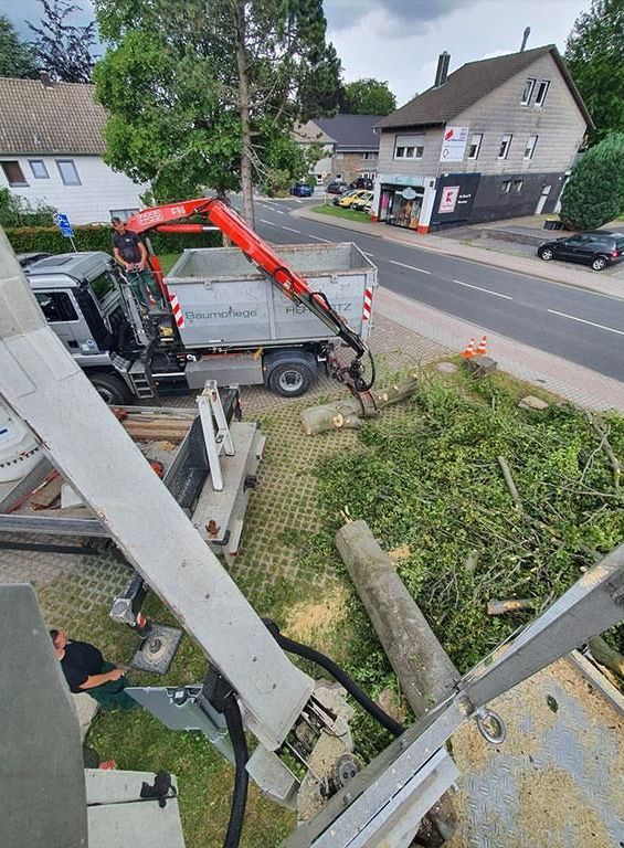 Ein LKW mit einem daran befestigten Kran fährt eine Straße entlang.