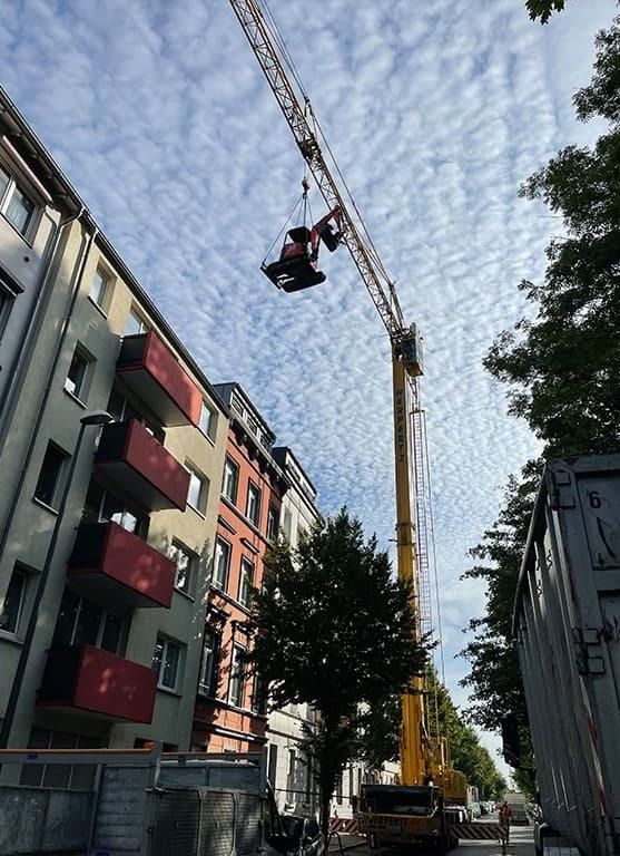 Ein Kran hängt vom Dach eines Gebäudes.