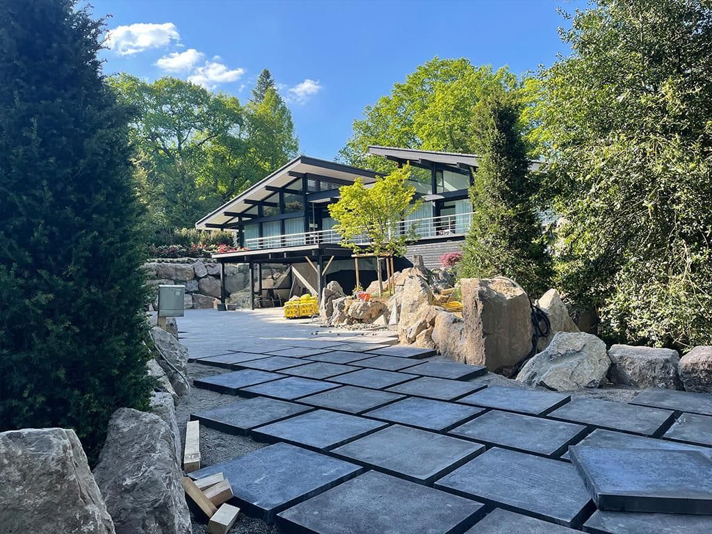 Ein großes Haus ist von Bäumen und Felsen umgeben.