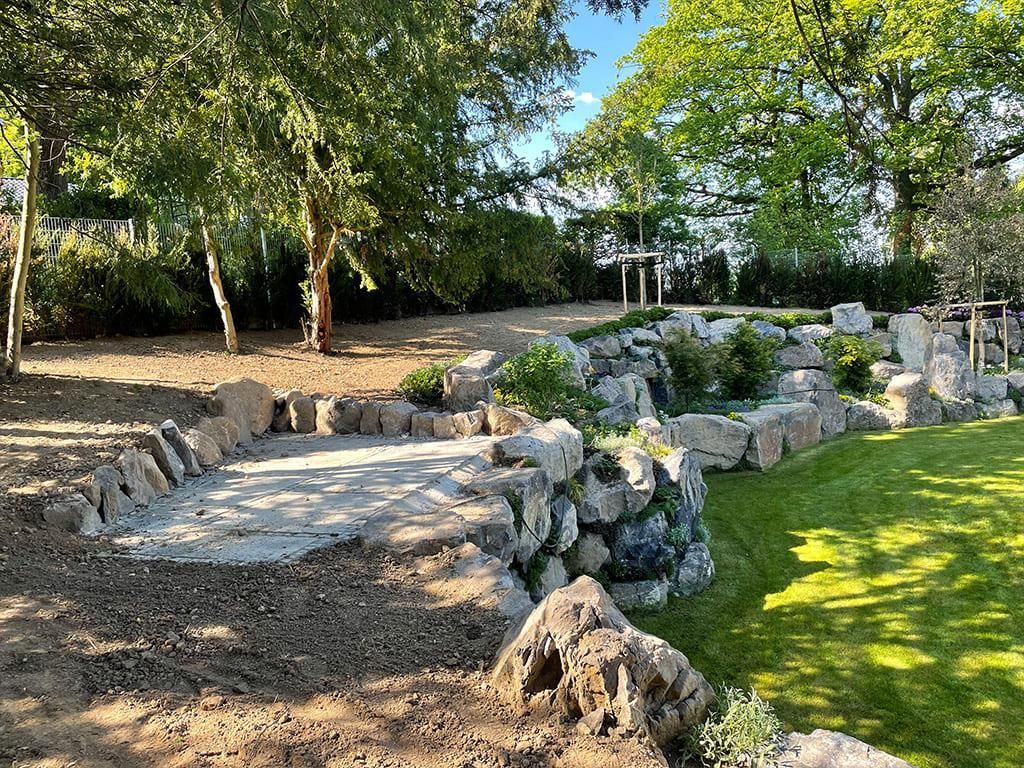 Eine große Felswand inmitten eines üppigen grünen Feldes, umgeben von Bäumen.