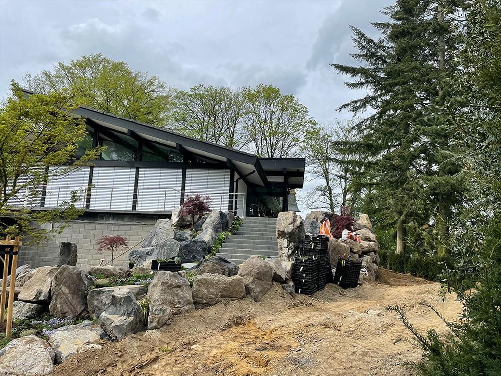 Auf der Spitze eines Hügels steht ein Haus, umgeben von Bäumen und Felsen.