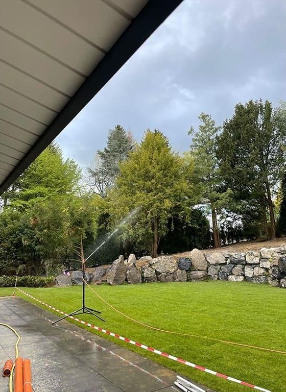 Ein Sprinkler sprüht Wasser auf ein üppiges grünes Feld.