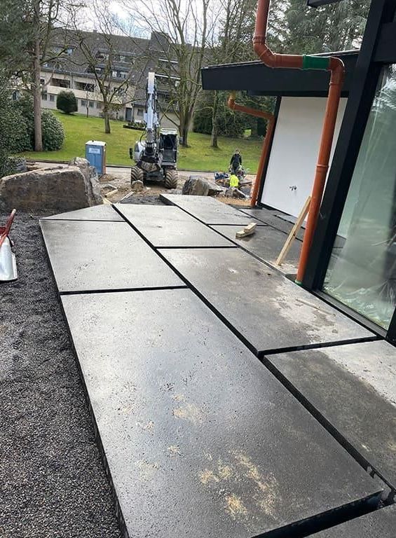 Vor einem Gebäude wird ein Betonweg gebaut.