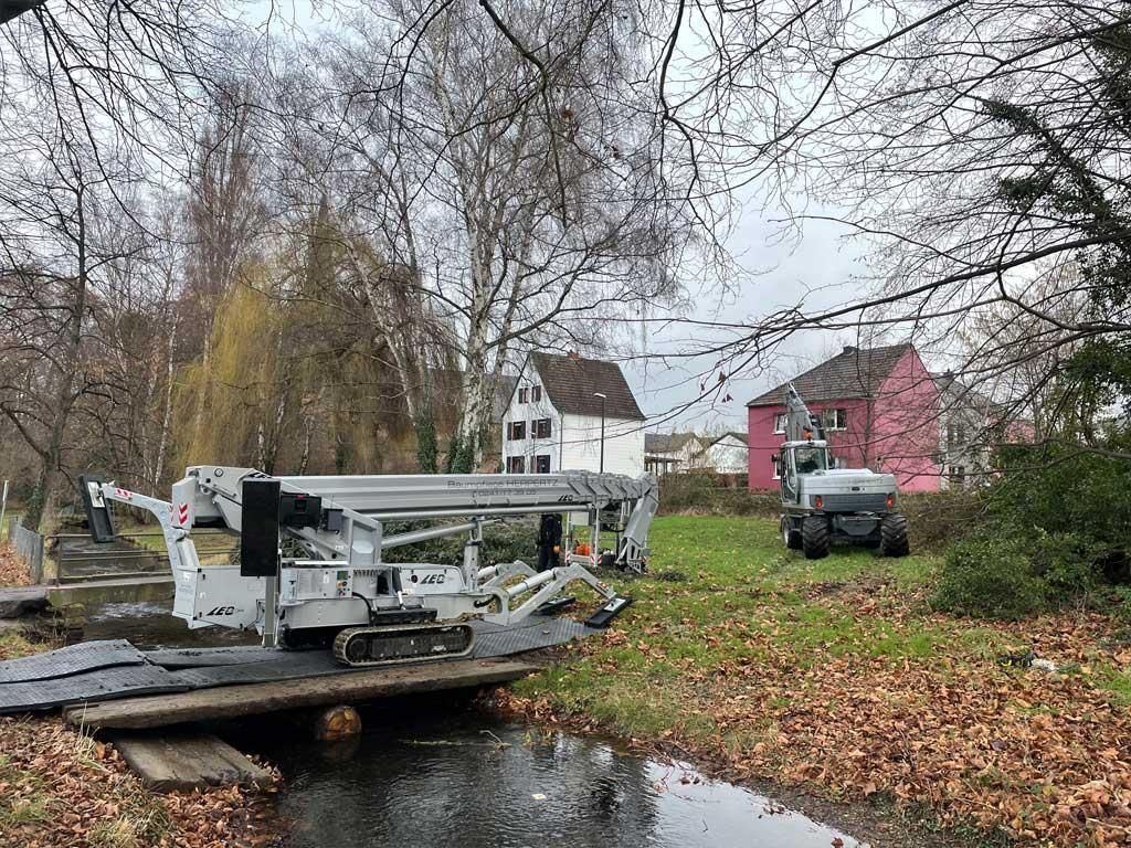 Ein Kran steht auf einer Holzbrücke über einem Fluss.
