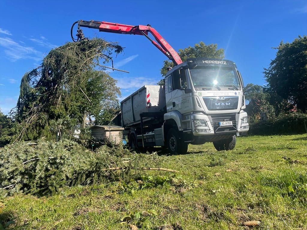 Ein LKW mit einem daran befestigten Kran fährt durch ein Grasfeld.
