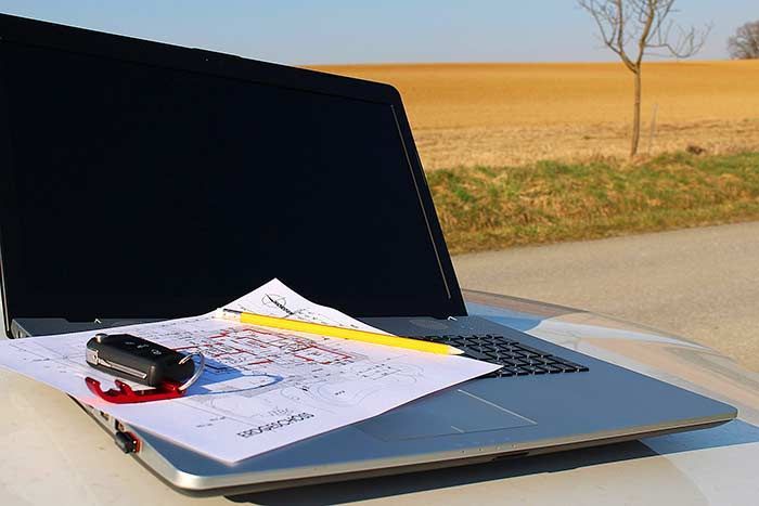 Ein Laptop liegt auf der Motorhaube eines Autos