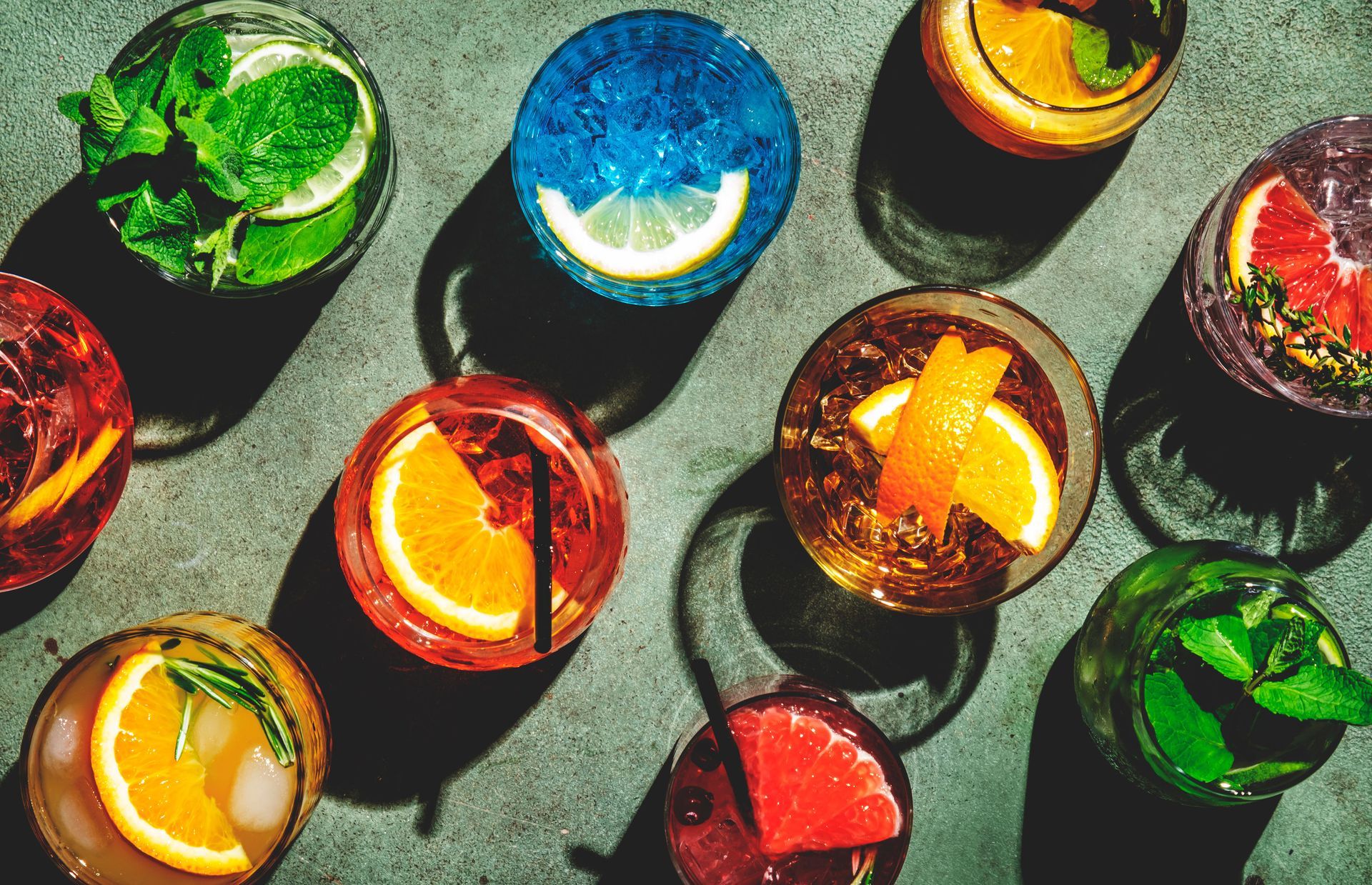 Una variedad de bebidas coloridas están sentadas sobre una mesa.