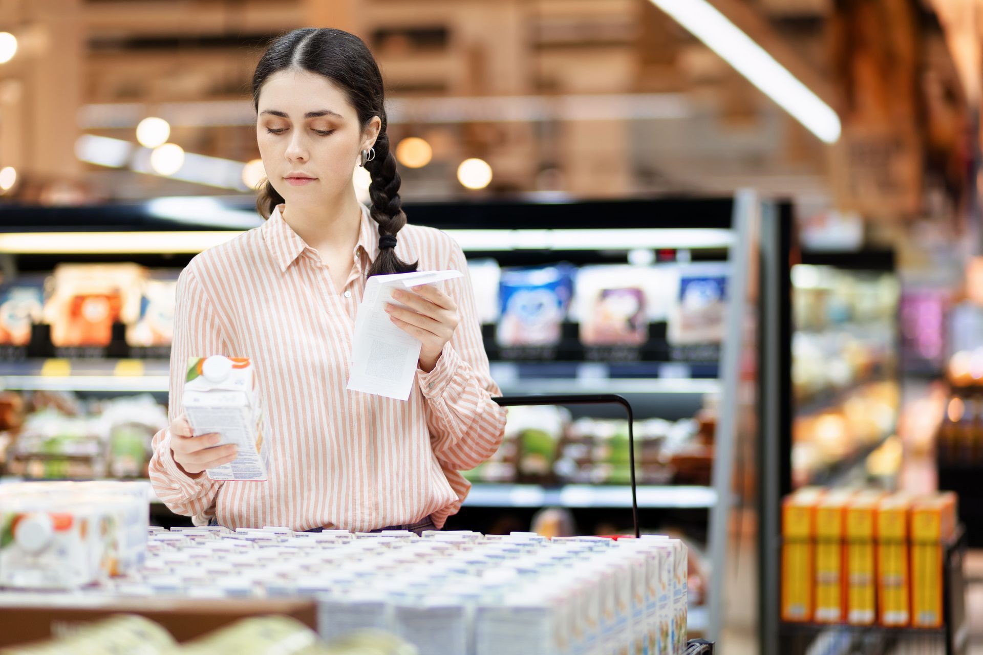 Una mujer está mirando una botella de leche en una tienda de comestibles.