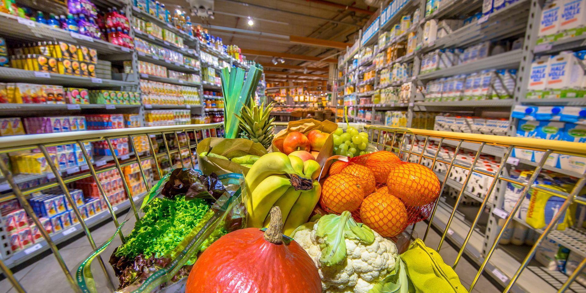 Un carrito de compras lleno de frutas y verduras en un supermercado.