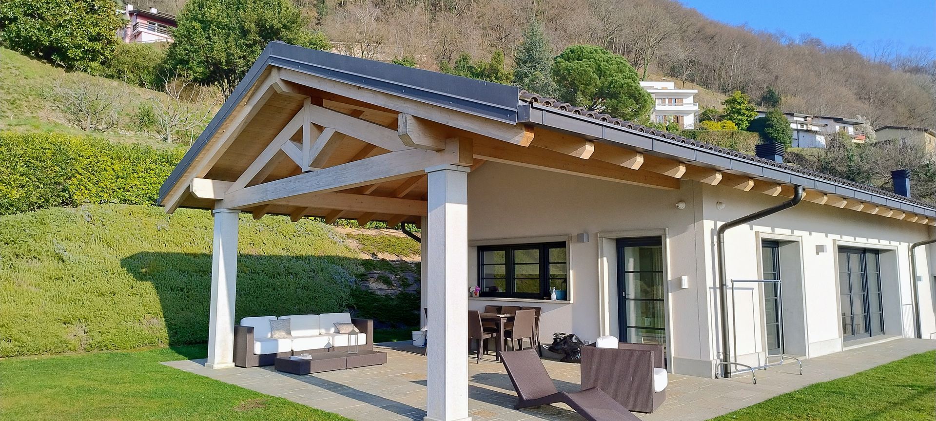 Una casa con patio e tetto in legno, con una montagna sullo sfondo.
