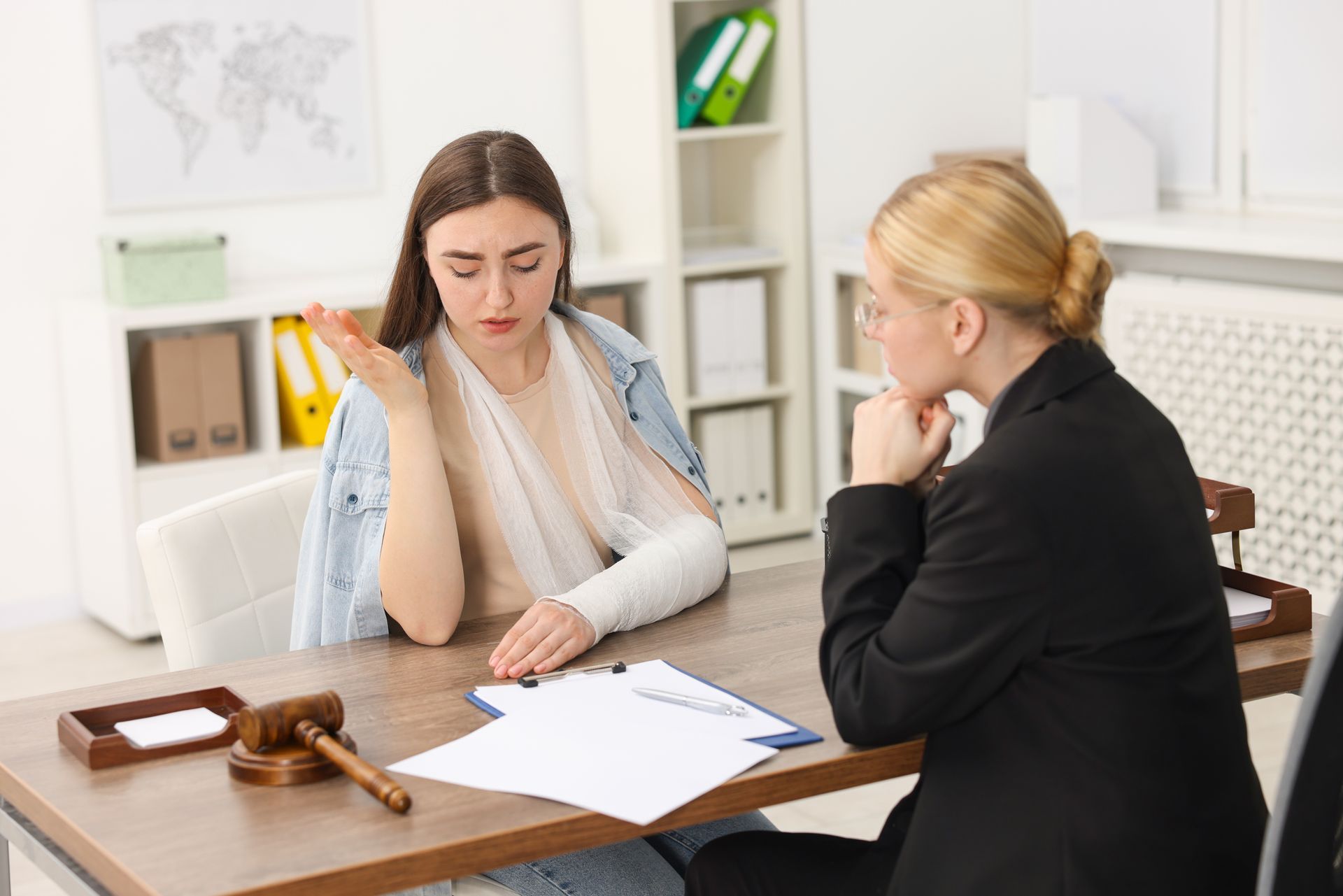 Une femme avec le bras plâtré rencontre un avocat dans son cabinet.