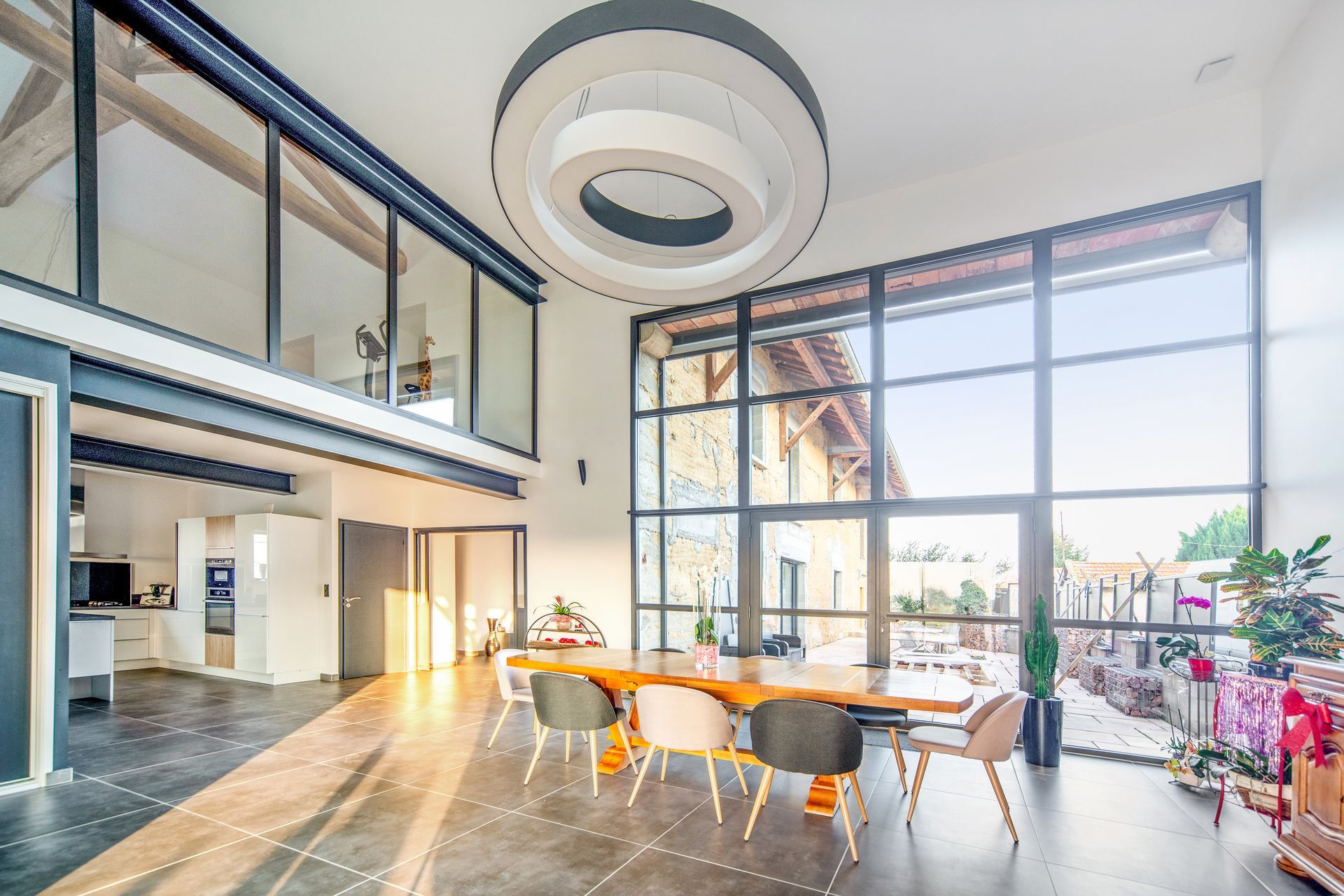 Salle à manger moderne de style loft avec de grandes fenêtres, une table en bois, des chaises
