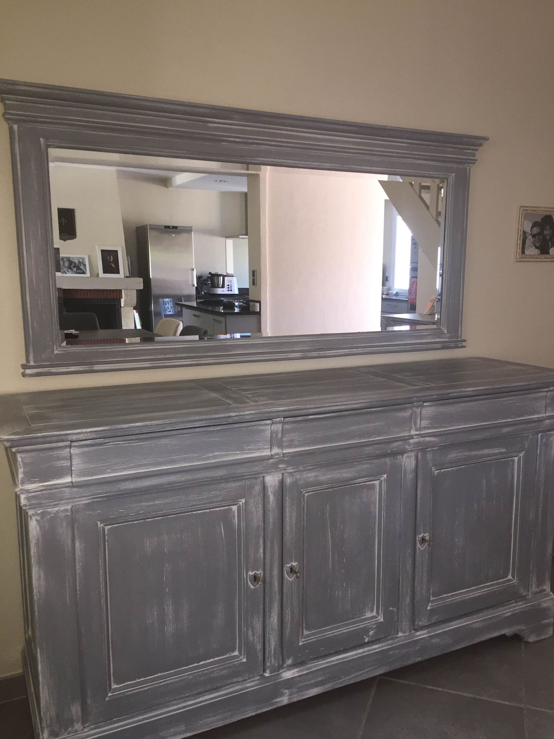 Buffet gris vieilli avec miroir dans un salon, reflétant une cuisine lumineuse derrière