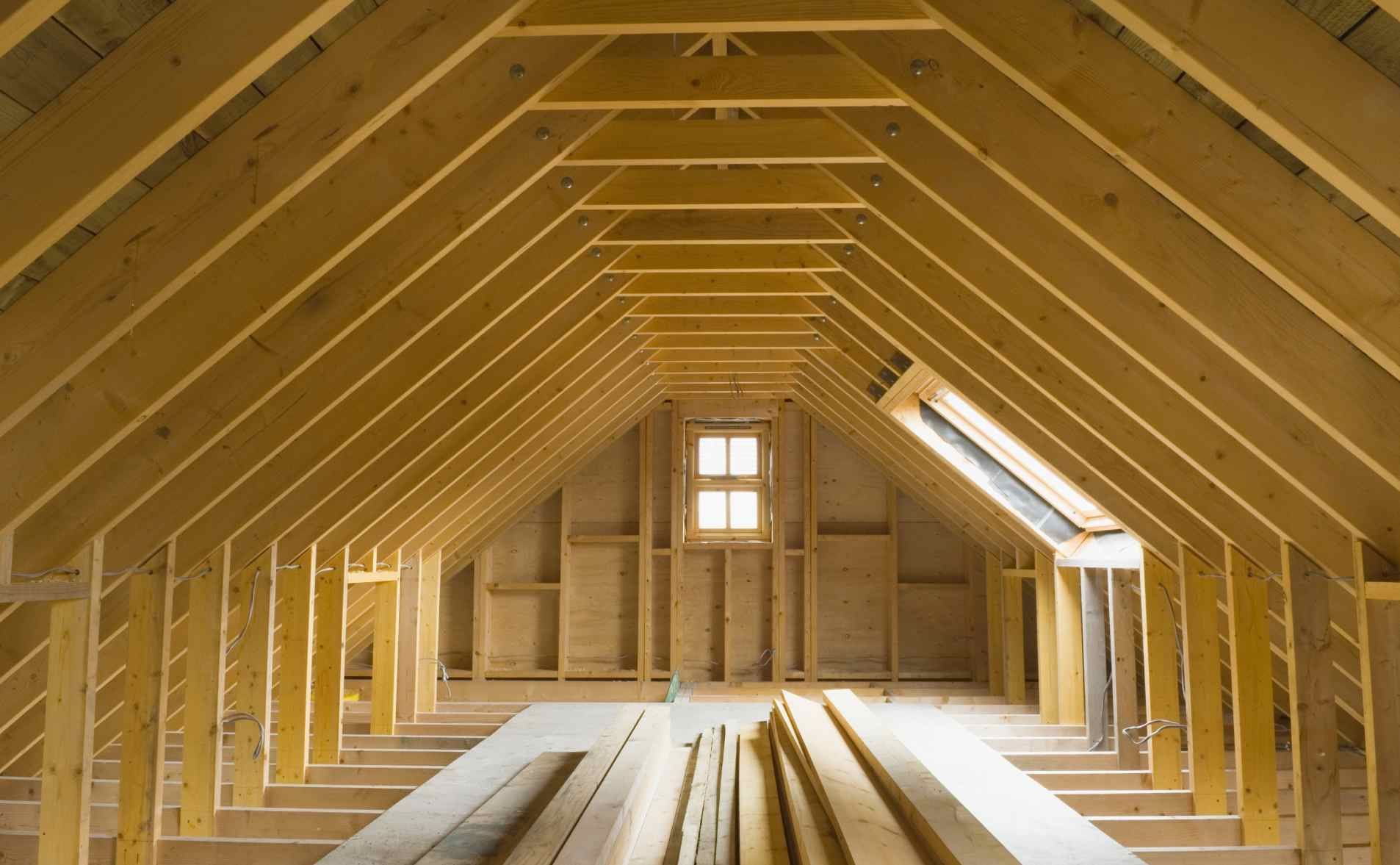 Grenier à ossature bois en cours d'aménagement, avec chevrons apparents, solives de sous-plancher