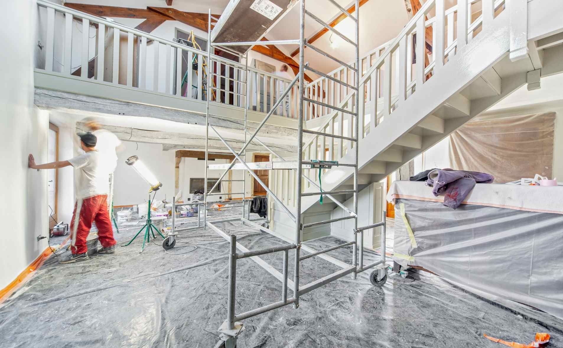 Des ouvriers peignent un intérieur d'un blanc éclatant, avec des escaliers et des échafaudages