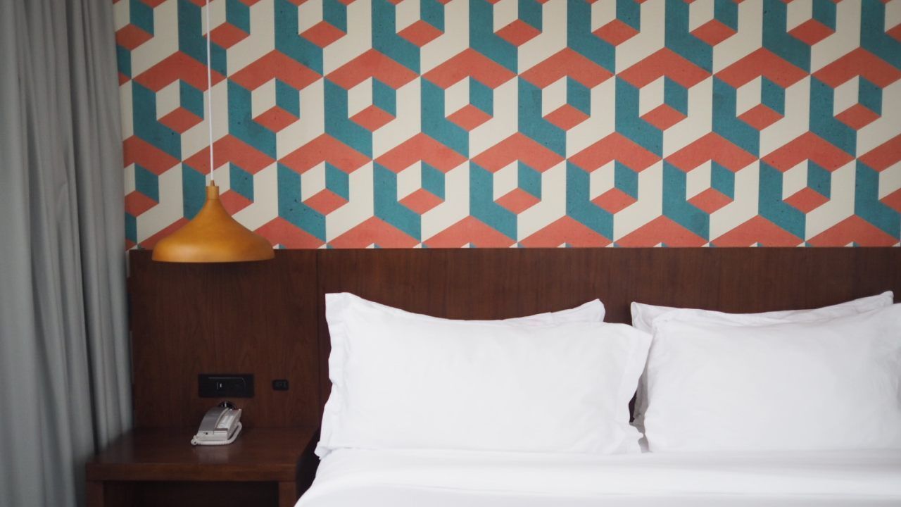 Lit d'hôtel avec oreillers blancs, tête de lit en bois, motif géométrique au mur