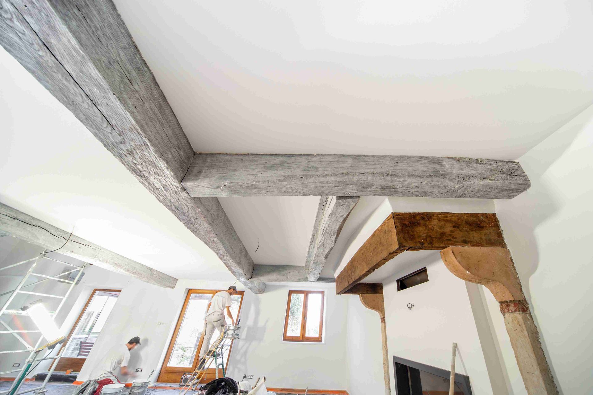 Pièce inachevée avec poutres de plafond en béton apparentes et une petite fenêtre.