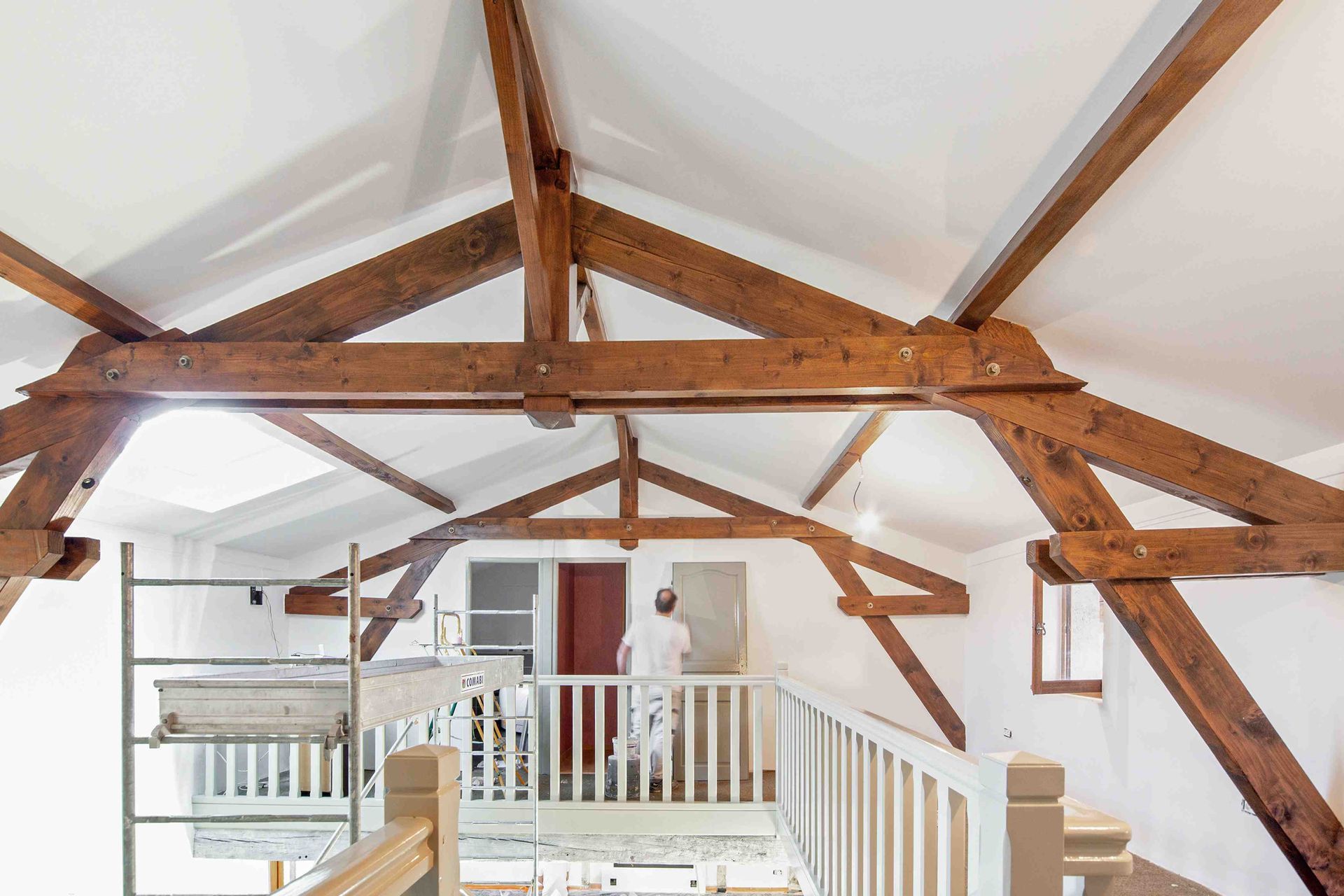 Intérieur de loft avec poutres apparentes, murs blancs et balustrade donnant sur l'espace