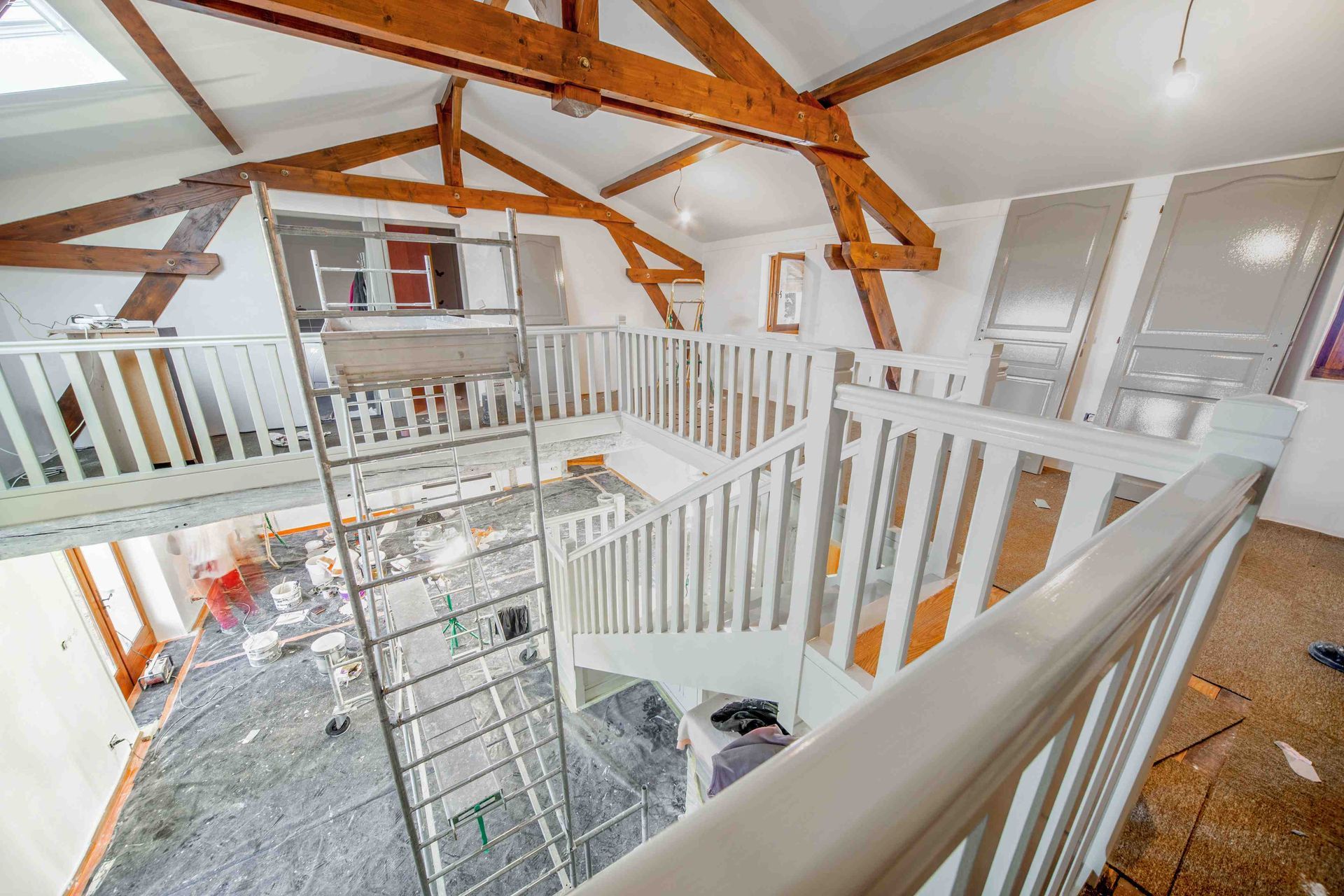 Loft lumineux et ouvert avec rambardes blanches, poutres apparentes et une grande échelle