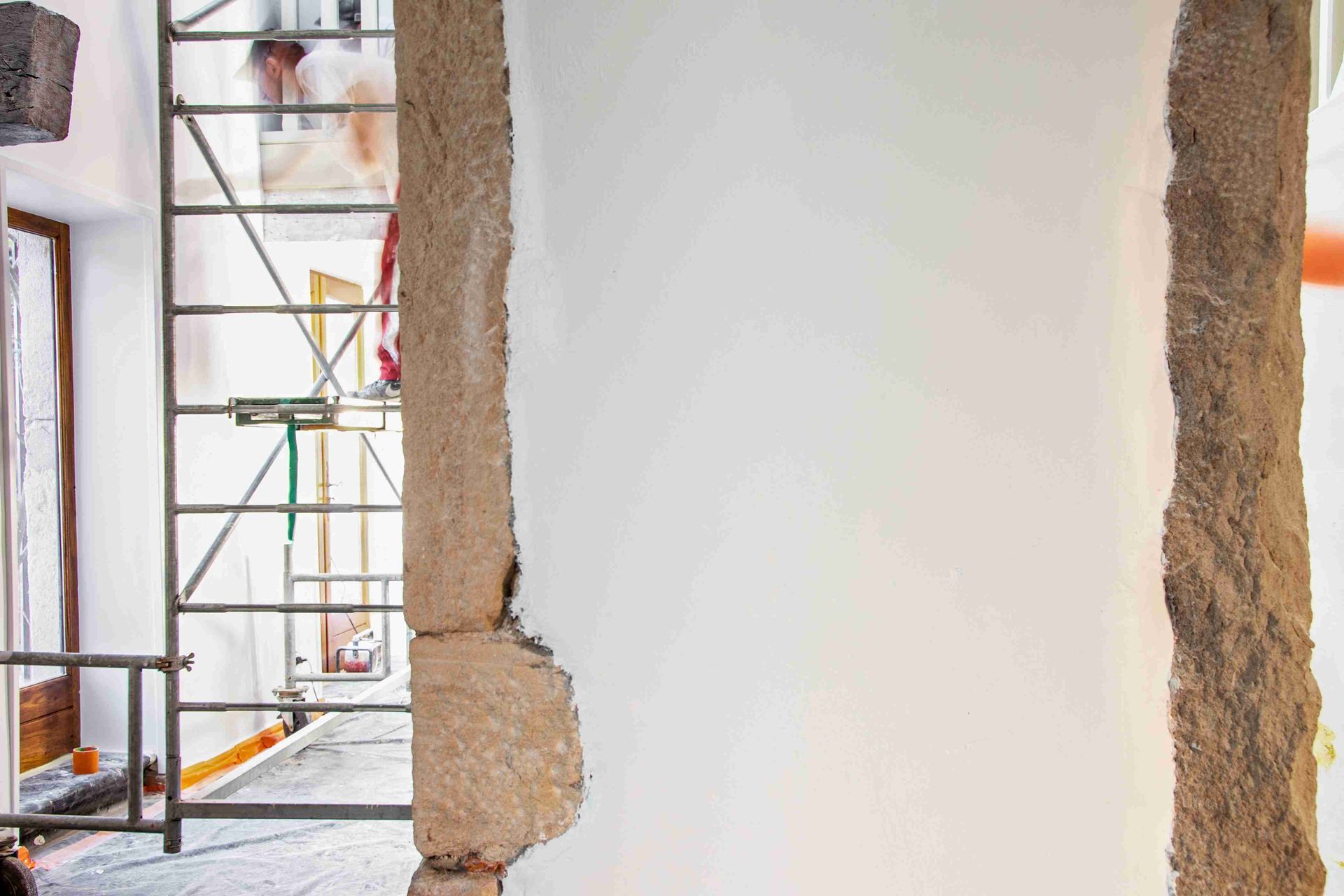 Échafaudages à l'extérieur d'un bâtiment en construction, à côté d'un mur enduit de plâtre blanc