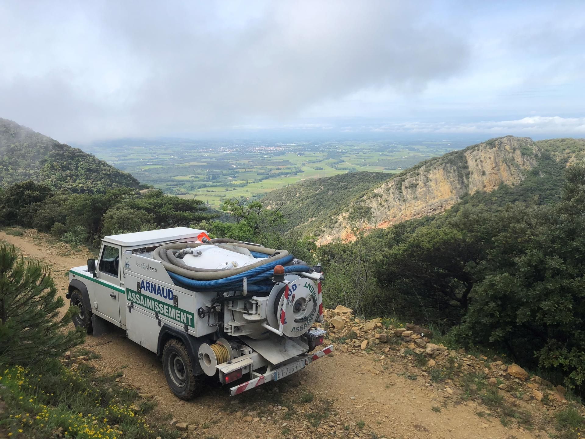 Camion blanc sur un chemin de terre dans un paysage montagneux avec vue sur la vallée.