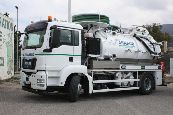 Camion de ramassage blanc avec le logo « ARNAUD ». Stationné à l'extérieur.