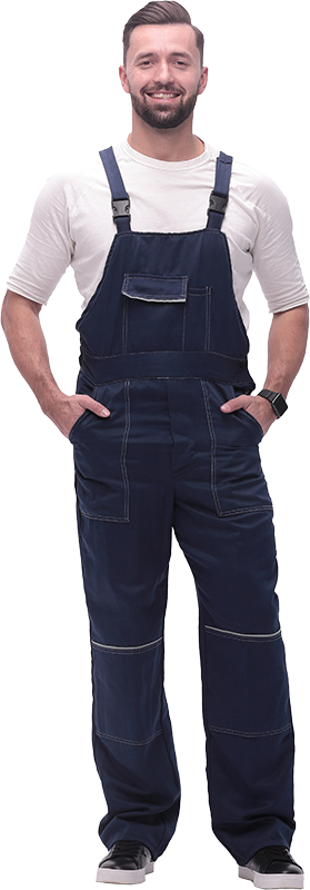 Un homme en salopette bleue sourit, les mains dans les poches.