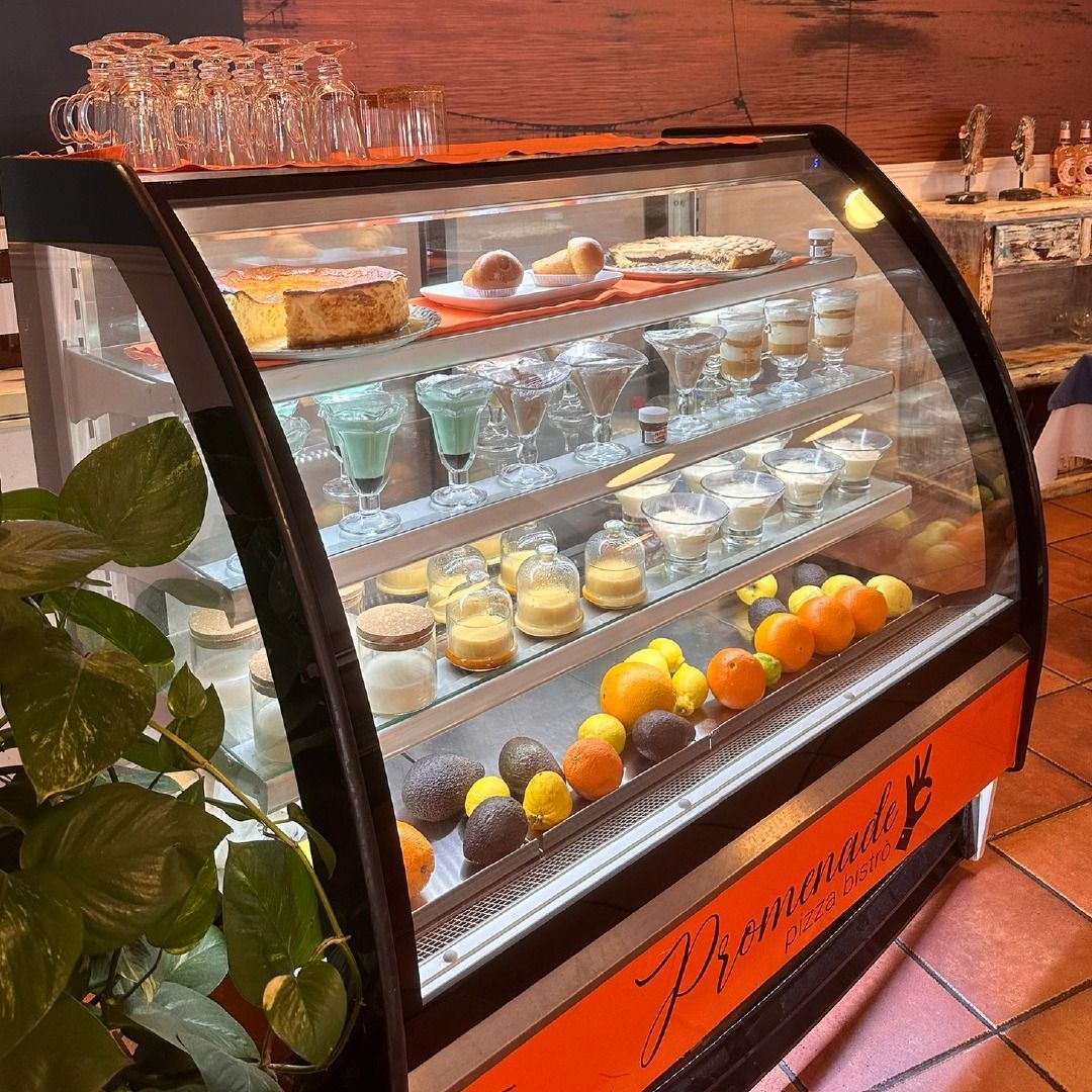 Una vitrina de postres llena de diversas delicias, incluidos pasteles, tartas y frutas, en un restaurante.