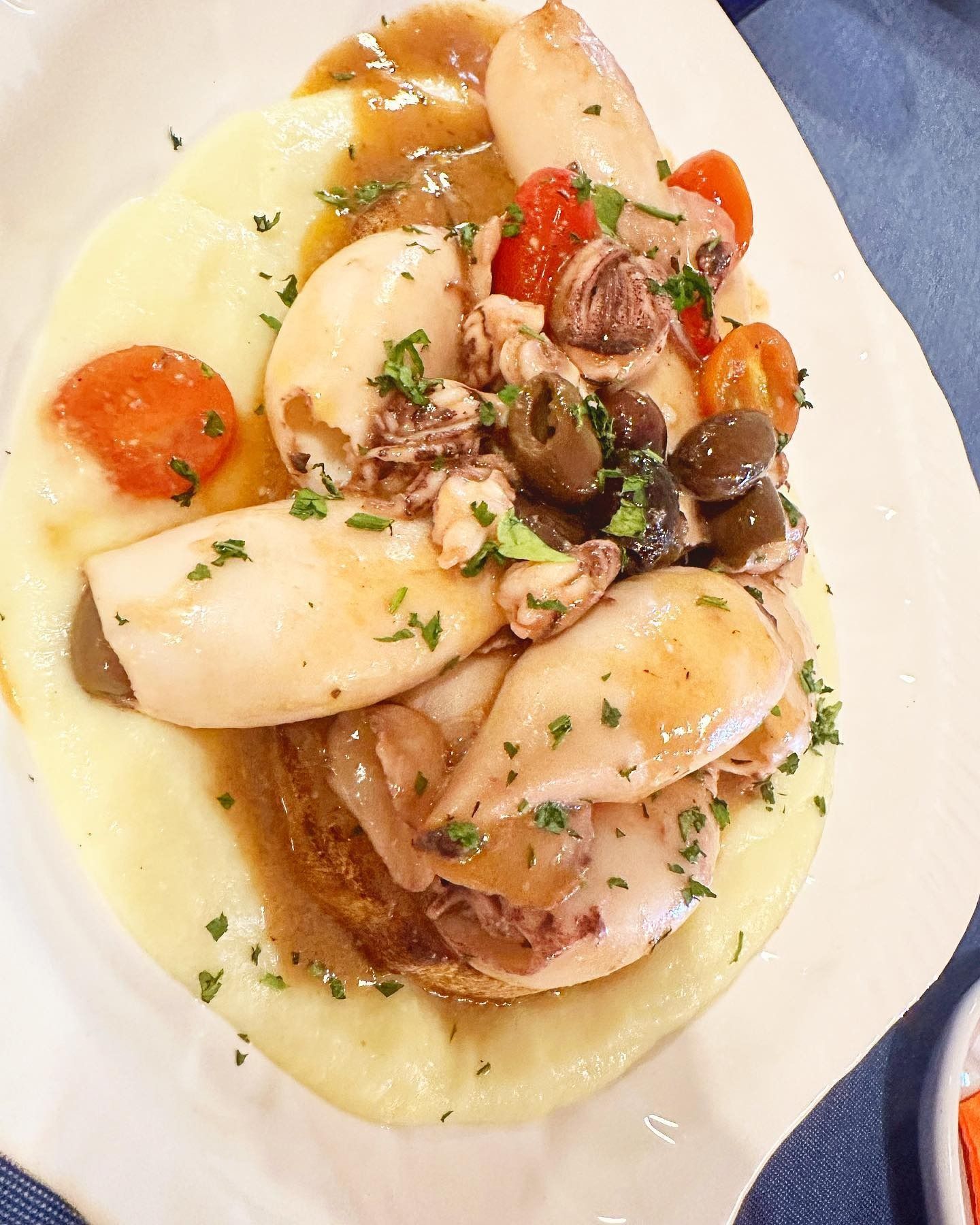 Filete de salmón, trozos de pescado blanco y sardinas en recipientes blancos sobre un mostrador.