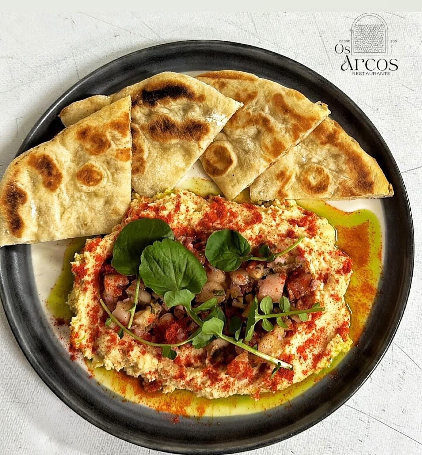 Un plato de comida con pan pita y hummus en una mesa.