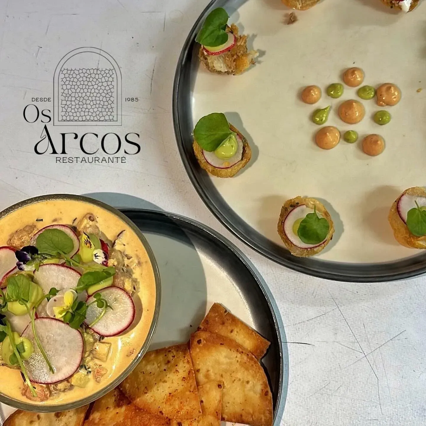 Tres platos de comida con el restaurante Os Arcos al fondo
