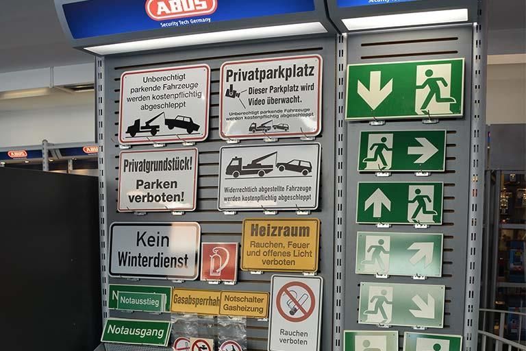 Ein Haufen Schilder an einer Wand, darunter eines mit der Aufschrift „Kein Mirerdienst“