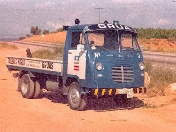Camión azul del GRU en un camino de tierra junto a un campo, con carga en la parte trasera.