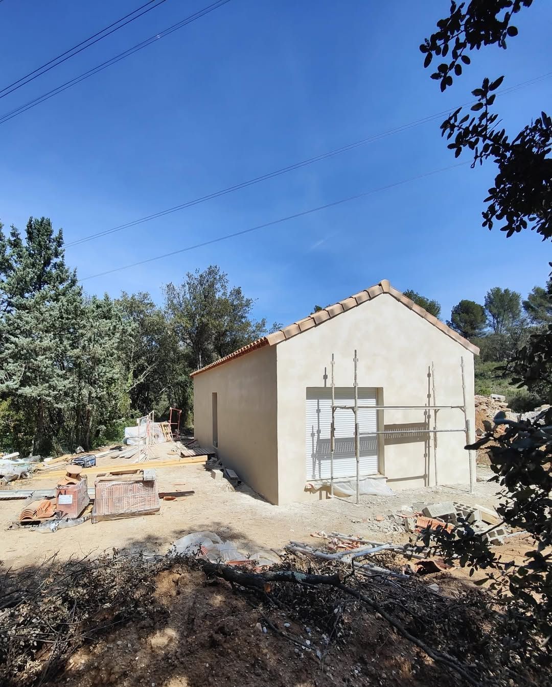 Une maison beige, de construction récente, avec un toit de tuiles rouges