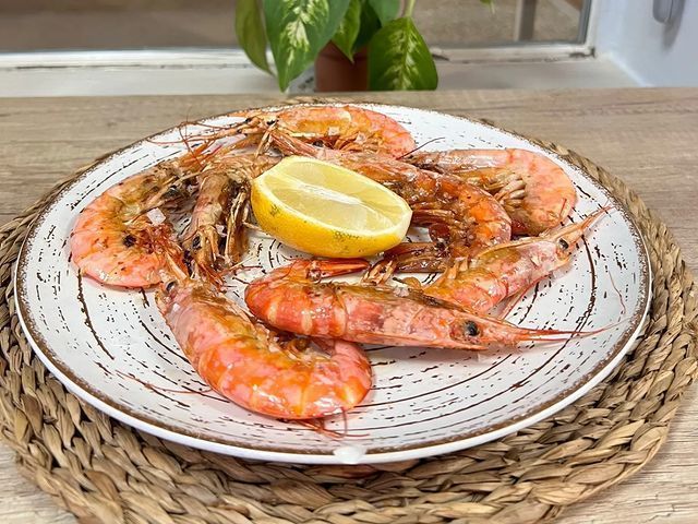 Un plato de camarones con una rodaja de limón sobre una mesa.