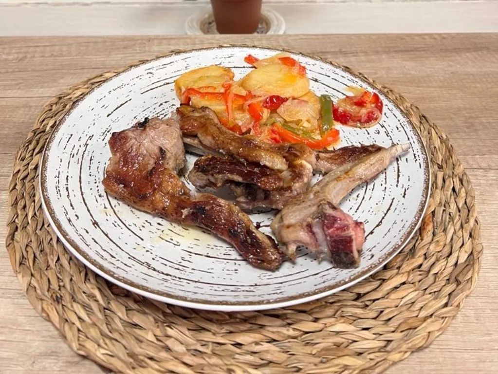 Un plato de comida con carne y verduras sobre un mantel sobre una mesa.