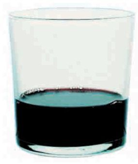 Un vaso lleno de líquido negro sobre un fondo blanco.