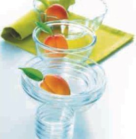 Un vaso de agua con naranjas sobre una mesa.