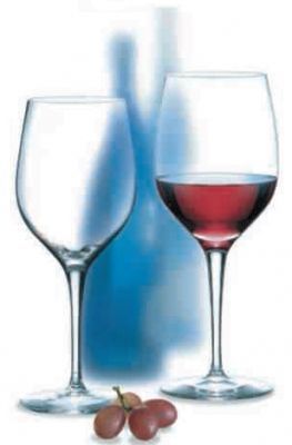 Dos copas de vino llenas de vino tinto y uvas delante de una botella.