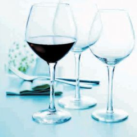 Tres copas de vino llenas de vino están sobre una mesa.