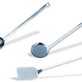 Una espátula, un cucharón y un colador están sobre una superficie blanca.