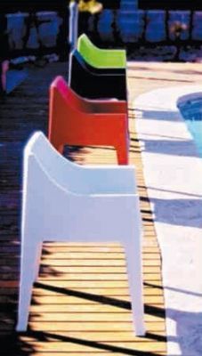 Una fila de sillas están alineadas al lado de una piscina.