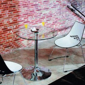 Una mesa de cristal con dos sillas frente a una pared de ladrillos.